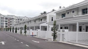 Eine Reihe moderner, weißer Gebäude mit Balkonen, eine klare Straße mit Richtungspfeilen und einige Bäume entlang des Bürgersteigs.