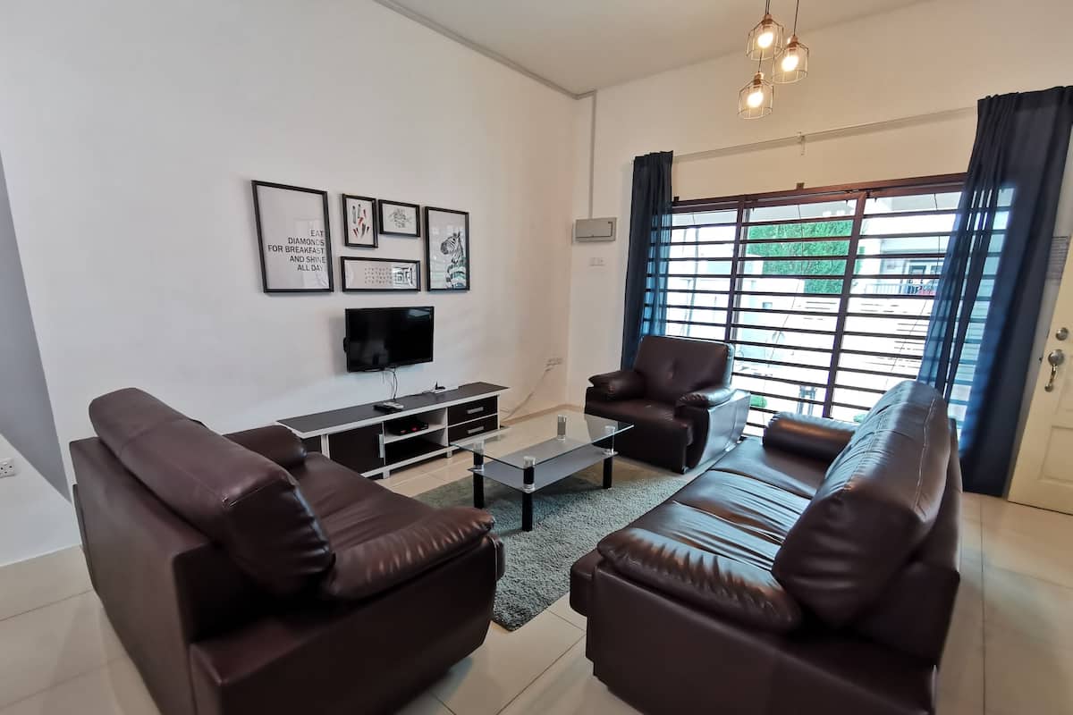 A modern living room with a sofa set, a coffee table, and a flat-screen TV.