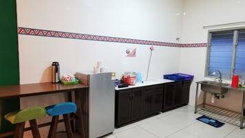 Una cocina compacta con refrigerador, pileta y ventana. Hay taburetes y una pequeña mesada.