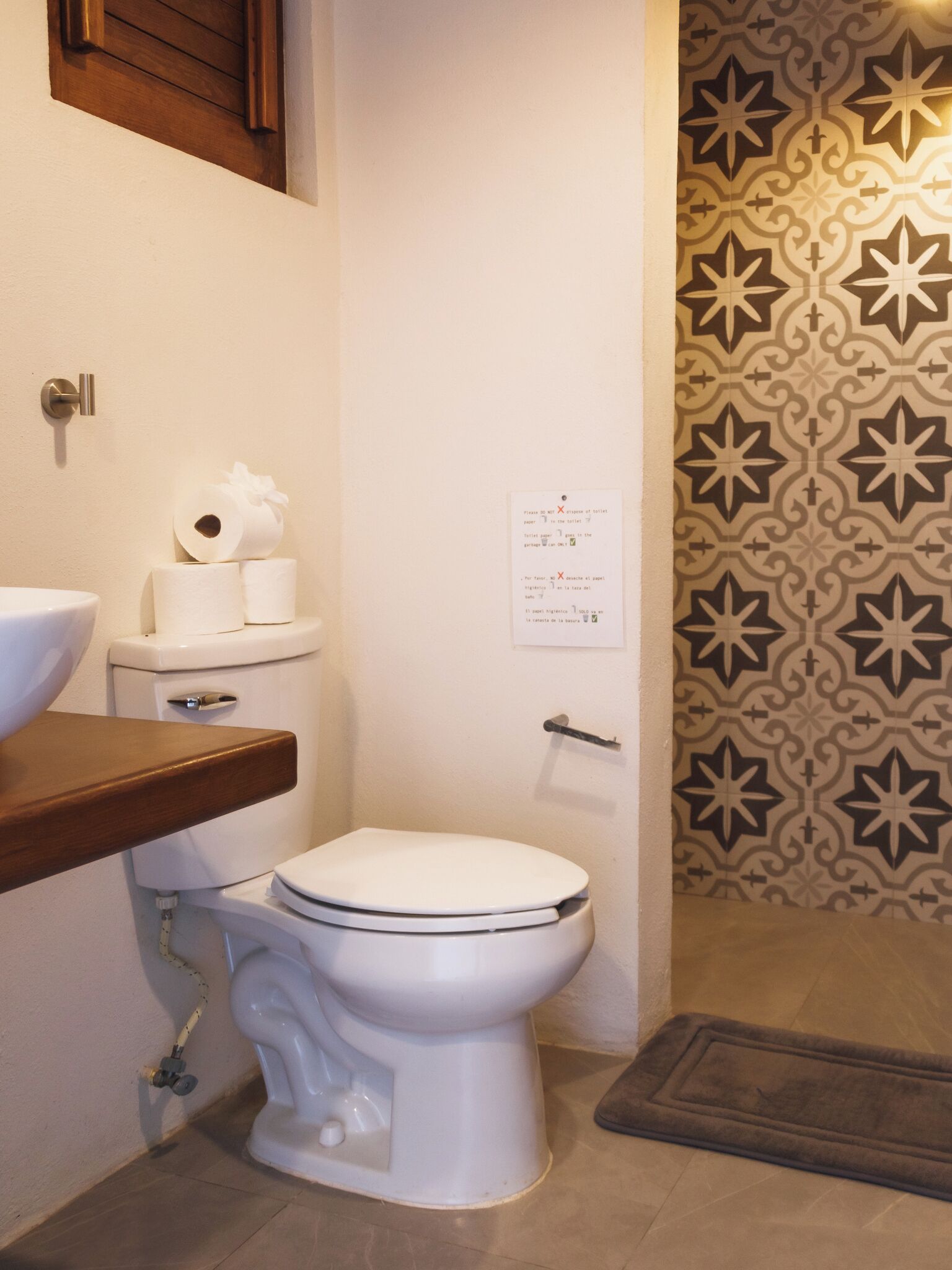 A bathroom with a toilet, a sink, and a patterned wall.