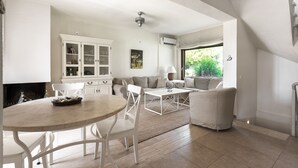 A modern living room with a dining area, white furniture, and a view of greenery outside. - Azapiko Dream Villa by Luxlikehome (Στυλαδάρι)