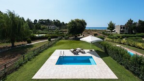A swimming pool with a view of the sea, surrounded by well-maintained lawns and hedges. - Azapiko Dream Villa by Luxlikehome (Στυλαδάρι)