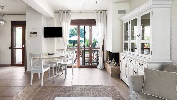 A spacious living room with a dining area, a fireplace, and a television mounted on the wall. - Azapiko Dream Villa by Luxlikehome (Στυλαδάρι)