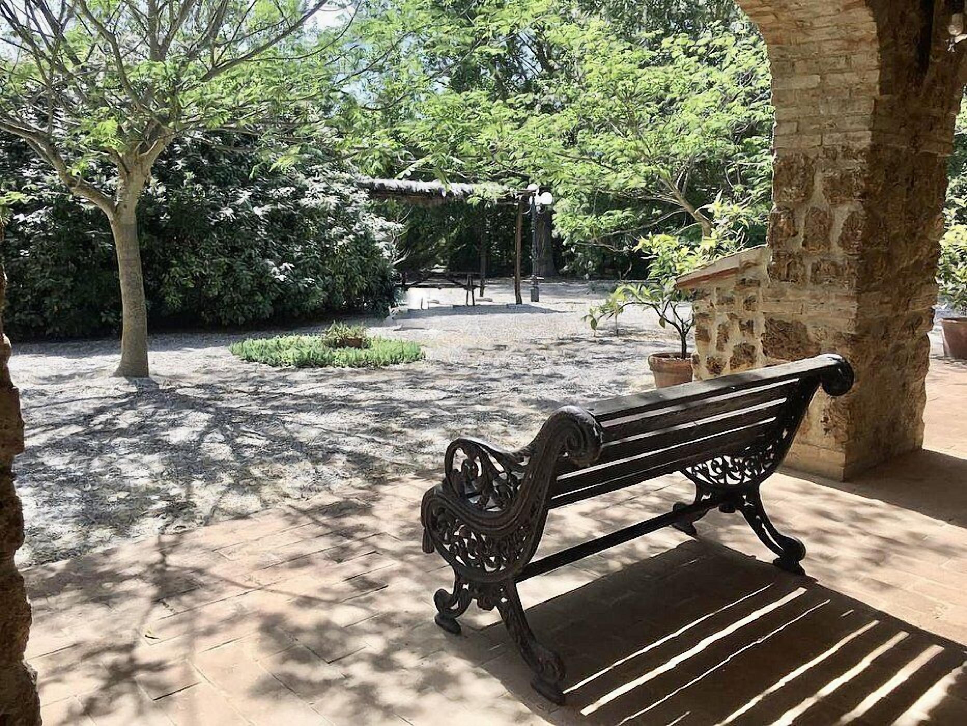 A bench in a courtyard with stone walls and potted plants.