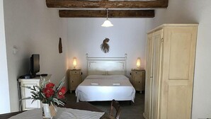 Ein Schlafzimmer mit Bett, Nachttischen, einem Holztablett mit Blumenvase und einem Kleiderschrank.