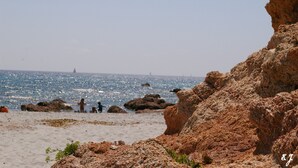 A rocky beach with clear blue water and a distant lighthouse. - Studio U Lilà, Wifi, Sea 6 km, Panoramic view of Aiguilles de Bavella (Sartène)