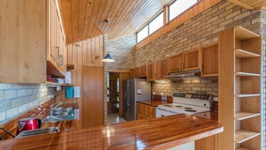 Une cuisine moderne avec des meubles en bois, un réfrigérateur en acier inoxydable et un grand îlot central doté d’un plan de travail en bois.