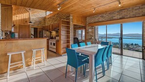 Une cuisine moderne avec des meubles en bois, un îlot central et un coin repas doté de chaises bleues.