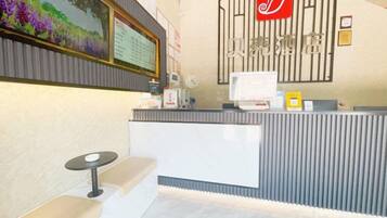 A reception desk with a computer, a seating area with a bench, and a wall-mounted sign.