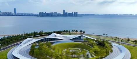A modern building with a circular design, surrounded by a landscaped area with trees and a pathway.