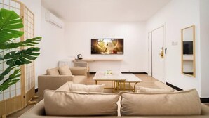 A living room with a sofa, a coffee table, a TV, and a plant. - Shell Hotel (Haikou hospital Hainan University store) (Qiongshan)