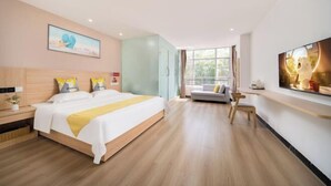 A modern hotel room with a large bed, a sofa, a TV, and a window with a view. - Shell Hotel (Haikou hospital Hainan University store) (Qiongshan)