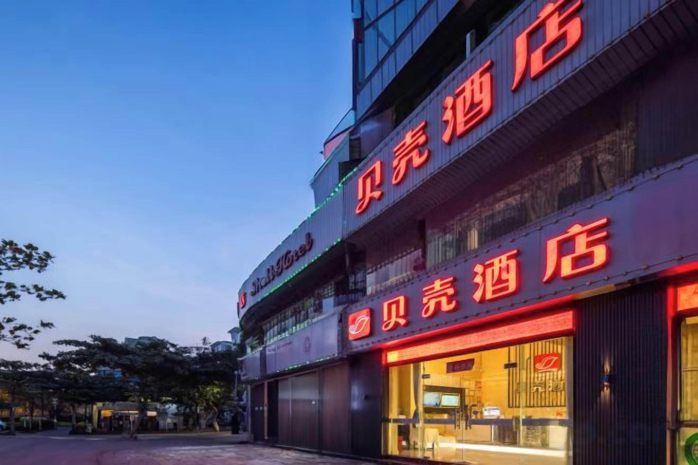 A hotel with a prominent red sign, multiple floors, and a well-lit entrance.
