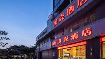 A hotel with a prominent red sign, multiple floors, and a well-lit entrance.