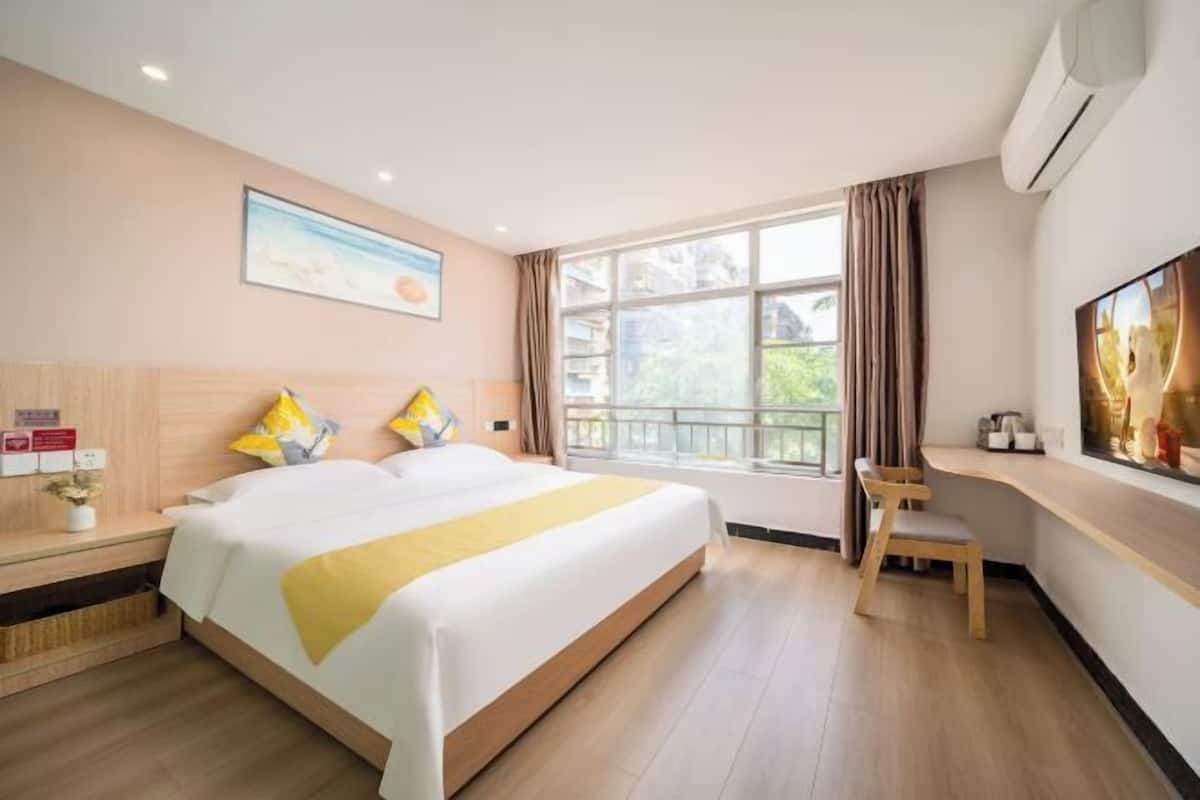 A hotel room with a large bed, a desk, and a window with curtains.
