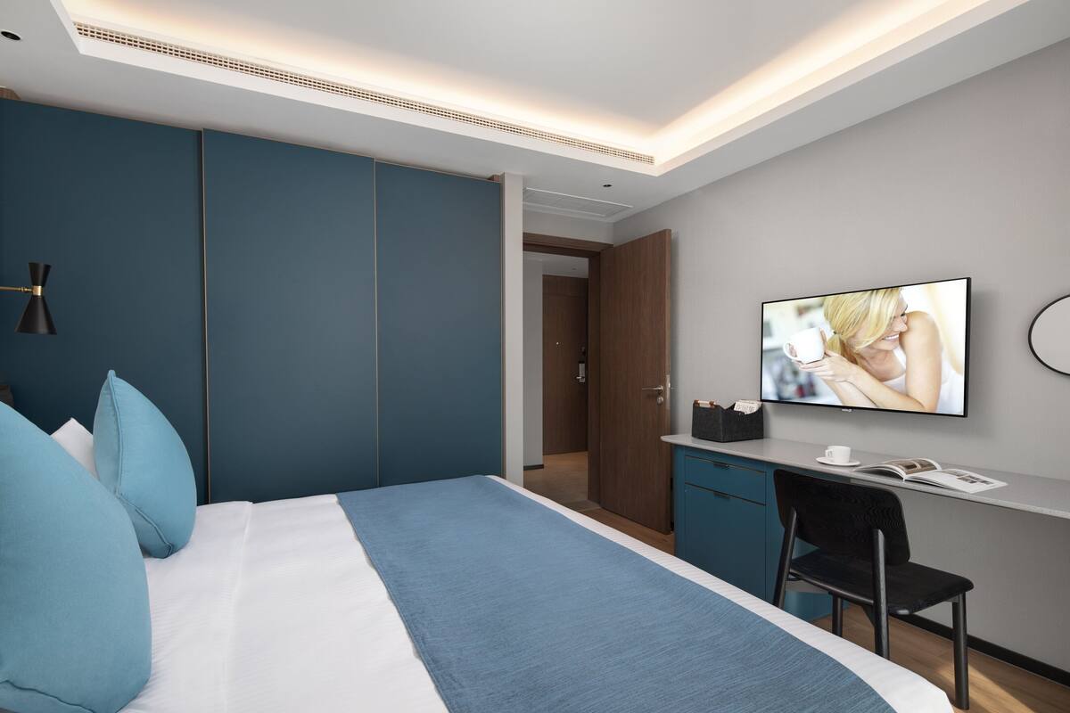 Una habitación de hotel moderna con cama, escritorio y televisor.
