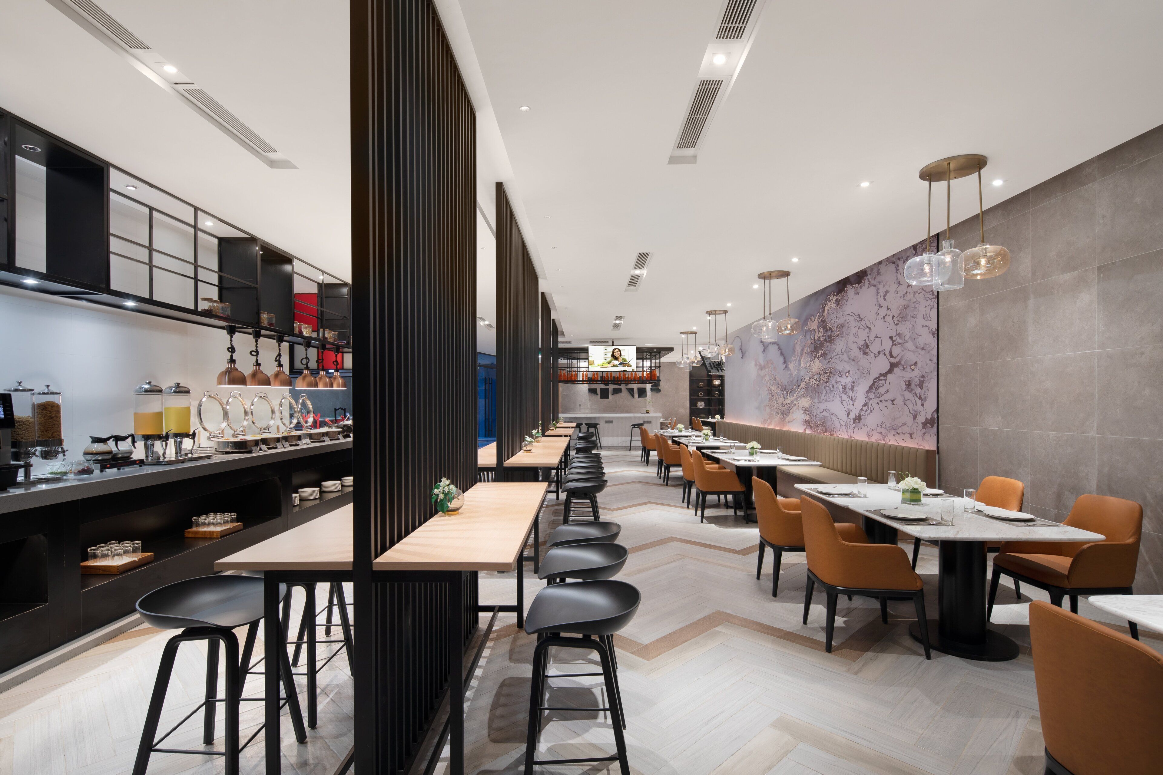 Un restaurante moderno con mesas largas comunitarias, taburetes negros de bar y una amplia pared de mármol.
