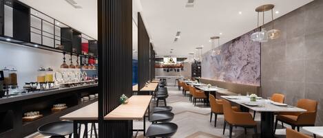 Un restaurante moderno con mesas largas comunitarias, taburetes negros de bar y una amplia pared de mármol.