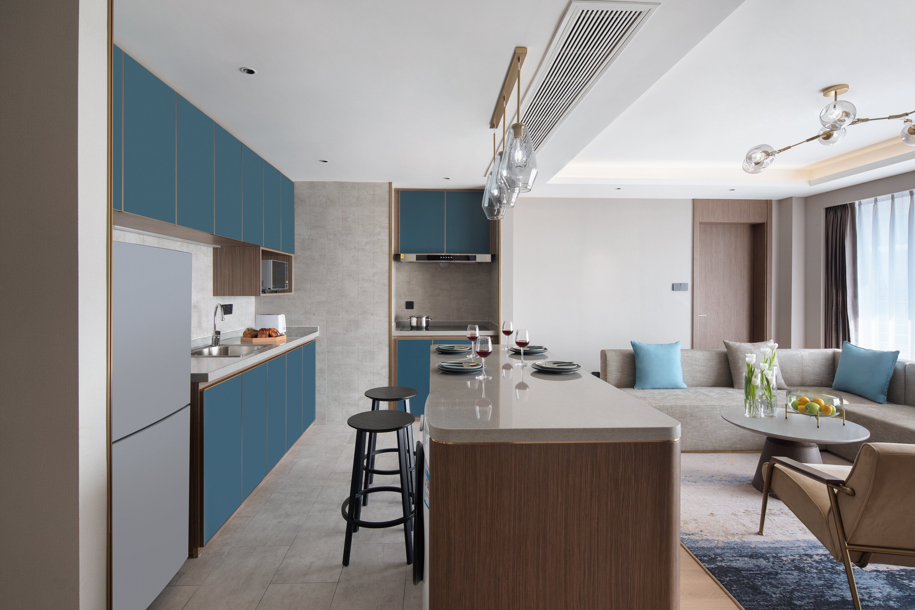 Una cocina moderna con armarios azules, una isla central y un comedor con una mesa redonda y taburetes de bar.