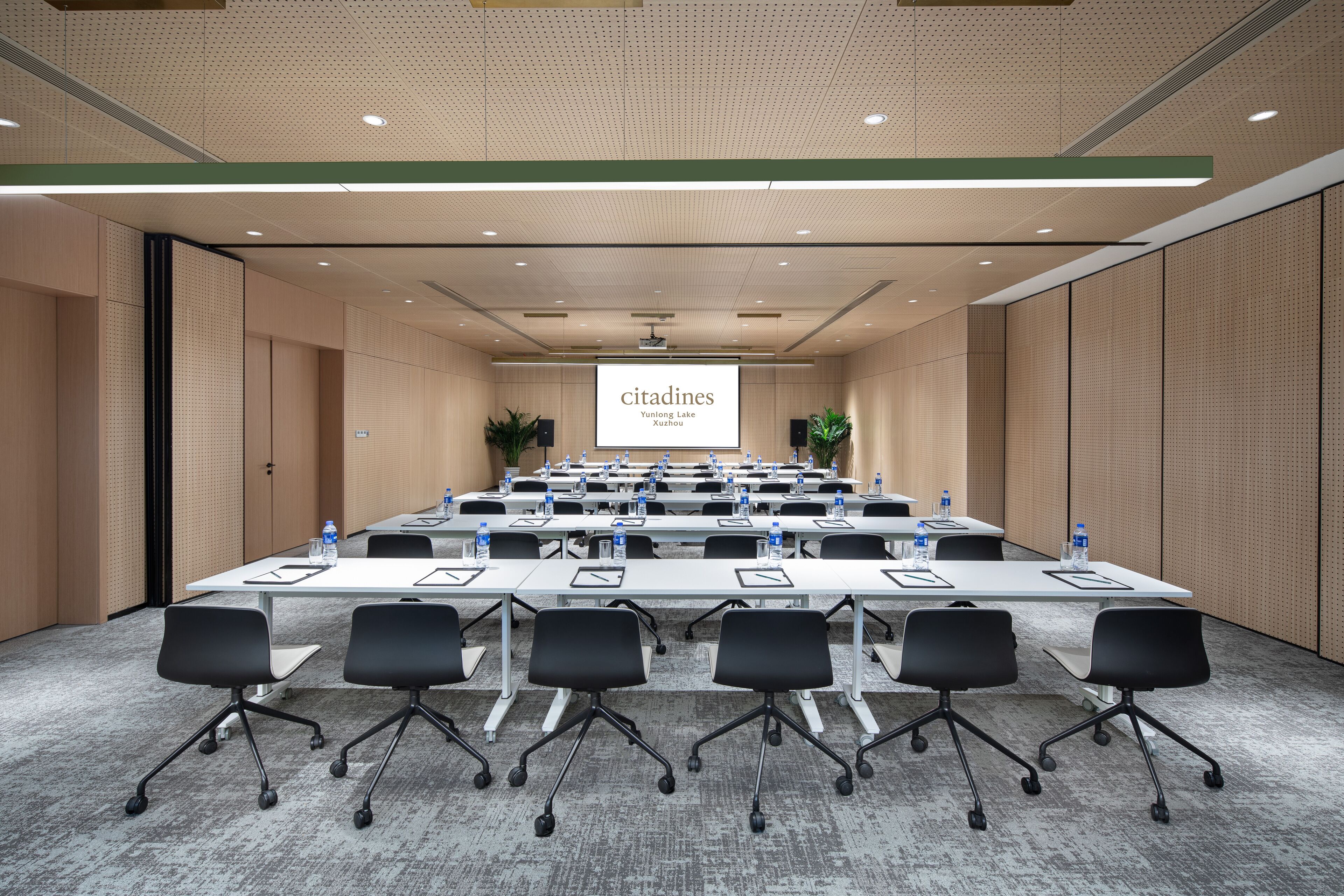 A conference room with a long table, multiple chairs, and a projector screen displaying "citadines".