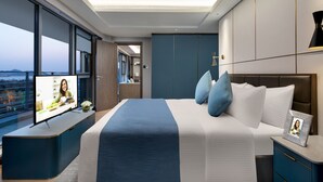 Une chambre d’hôtel moderne avec un grand lit, un téléviseur posé sur une console et une vue sur la ville.
