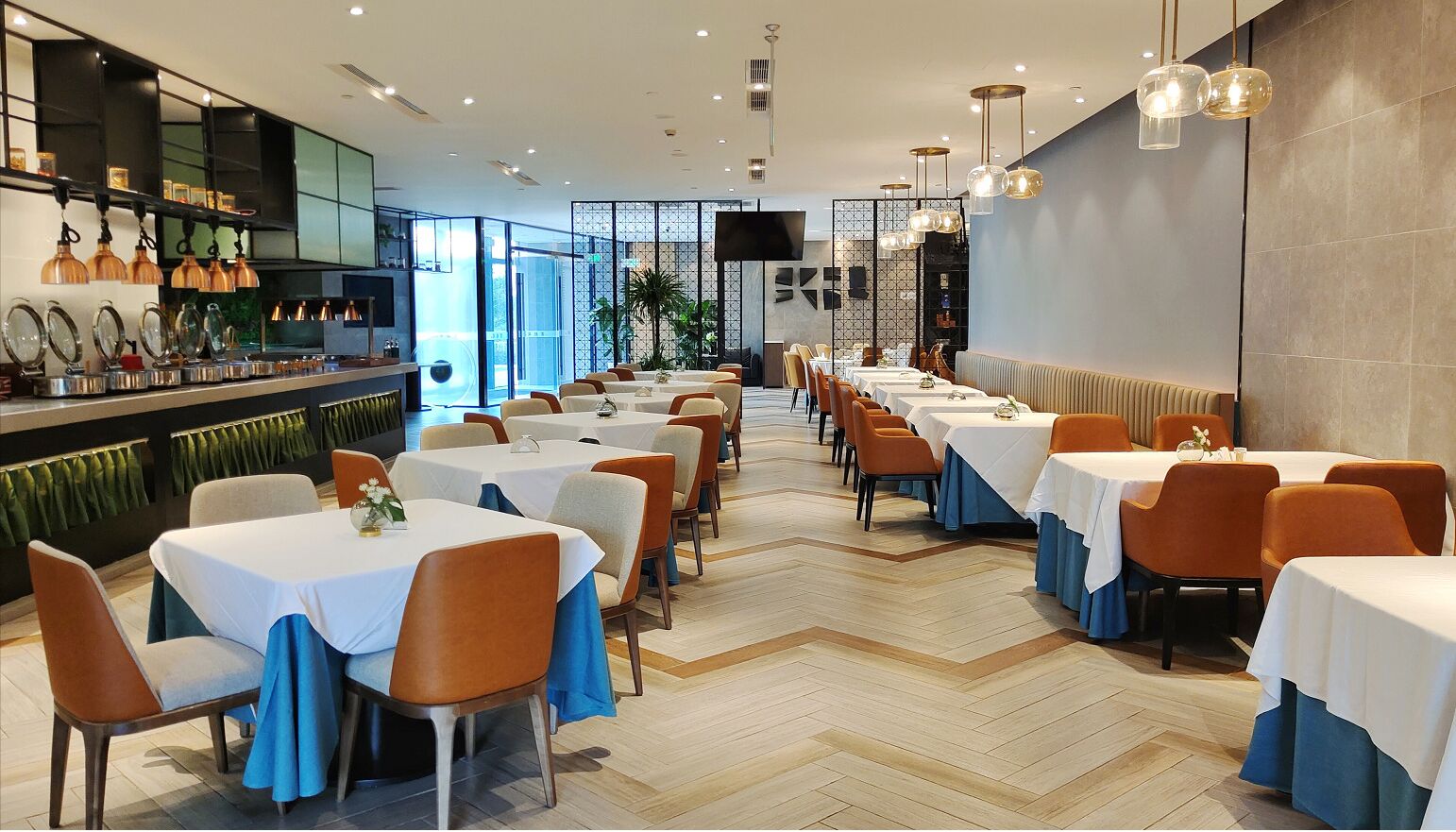 Un restaurante moderno con varias mesas y sillas, una zona de bar y una pantalla grande.