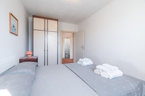 Een hotelkamer met twee bedden, een nachtkastje met een lamp, een spiegel en een deur naar een badkamer.