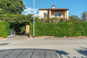 A two-story building with a tiled roof, surrounded by dense greenery and a clear sky. - Apartment Rokov (Rovinj)