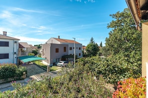 A residential area with houses, a covered outdoor seating area, and a car parked in front. - Apartment Rokov (Rovinj)