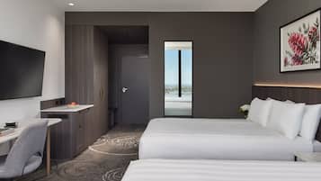 A modern hotel room with a large bed, a desk, and a TV.
