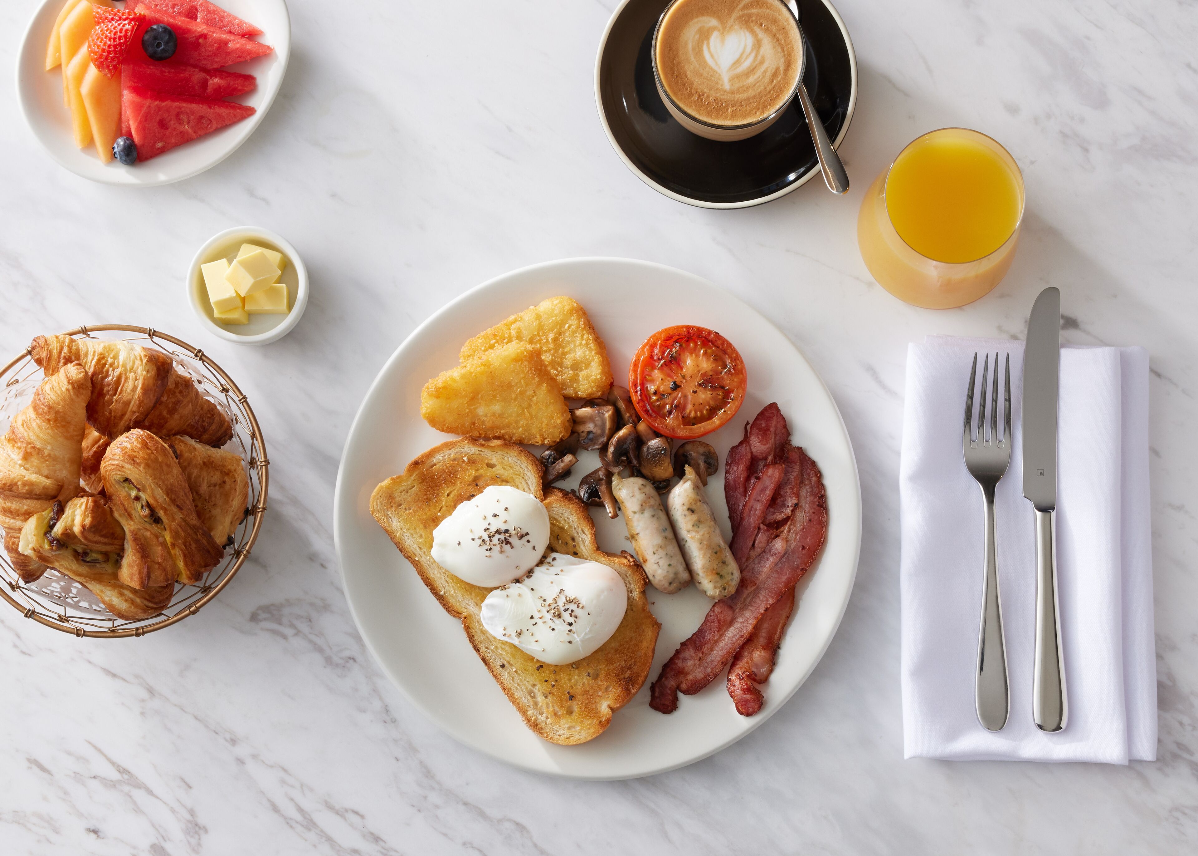 A breakfast plate with toast, eggs, bacon, mushrooms, and a tomato.
