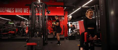 A gym with various exercise equipment, including a squat rack and weight machines.