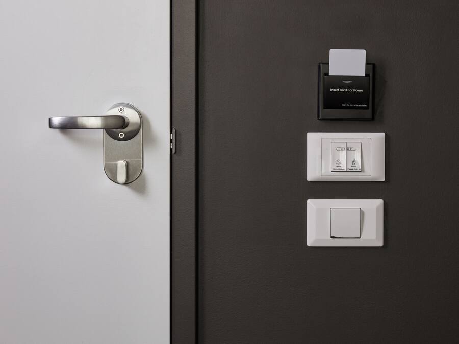 Una puerta moderna con lector de tarjetas, toma de corriente y pulsador de luz.