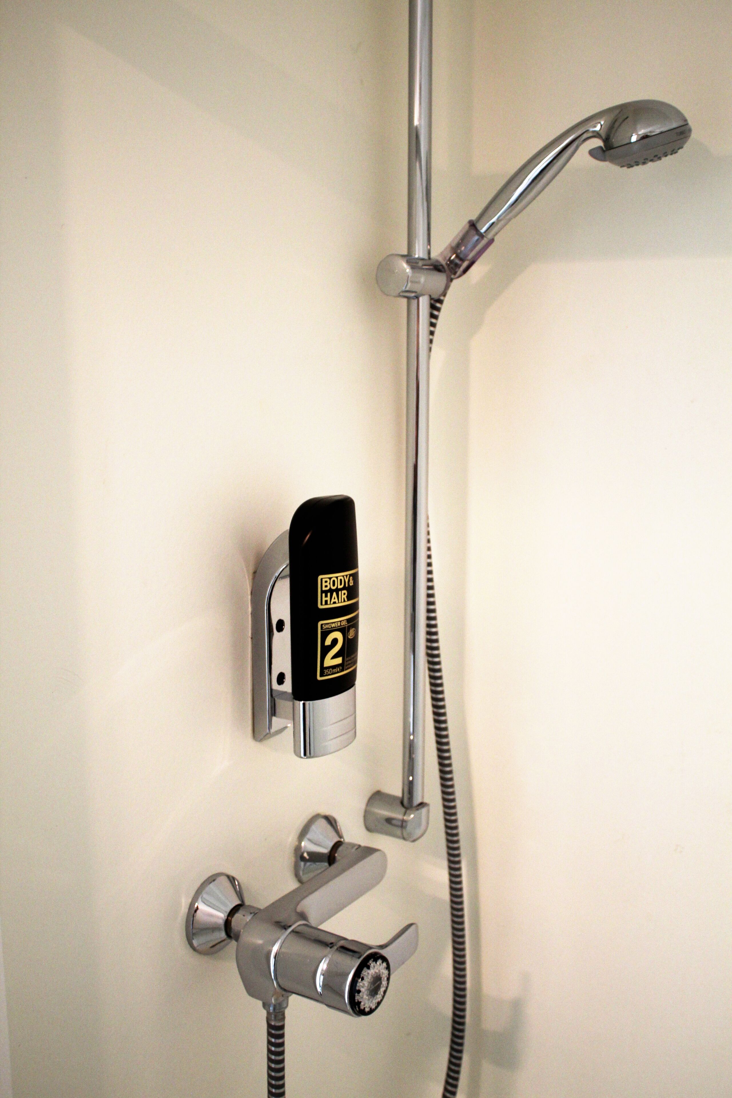Eine Dusche mit Handbrause und Kopfbrause, beide an der Wand befestigt.