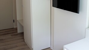 A room with a white wardrobe, a flat-screen TV mounted on the wall, and a wooden floor. - Bendorf Hotel by Belvilla (Bendorf)
