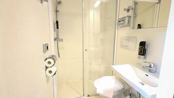 A bathroom with a glass shower enclosure, toilet, and sink.