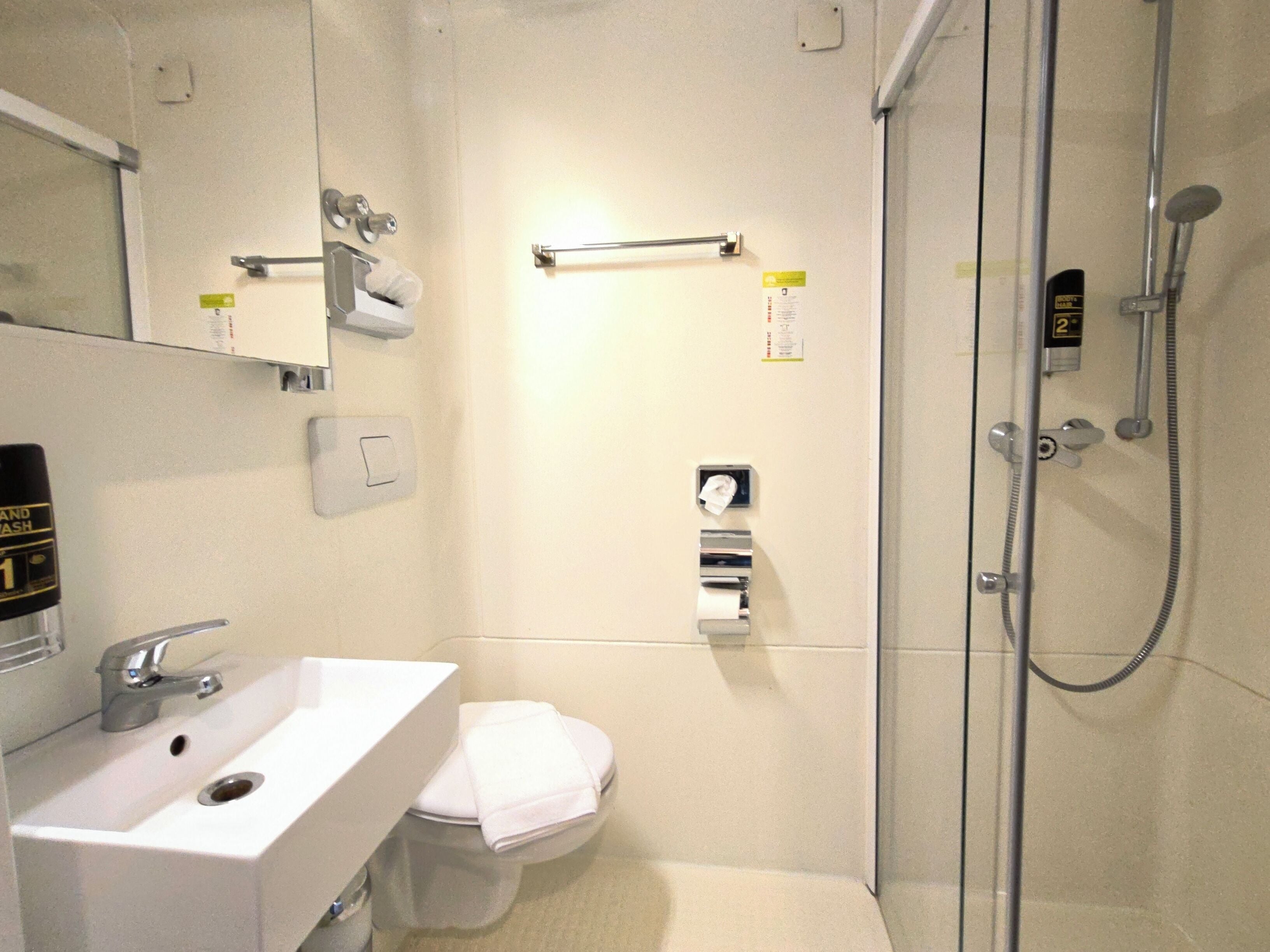 Une petite salle de bain moderne avec un lavabo blanc, des toilettes et une douche à parois de verre.