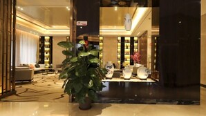Un vestíbulo moderno con una planta grande en maceta, una zona de estar con sofás y una exhibición de jarrones decorativos.