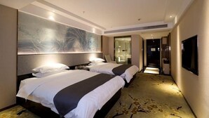 Habitación de hotel con dos camas, un cuadro abstracto grande en la pared, un televisor y piso alfombrado.