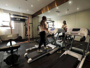 Un gimnasio con cintas de correr, una banca de pesas y una estructura para sentadillas.