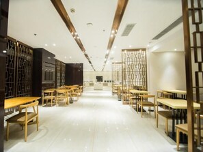 A modern restaurant interior with wooden tables and chairs, a central aisle, and decorative panels. - Greentree Eastern Jingde Town Railway Station Hotel (Jingdezhen)