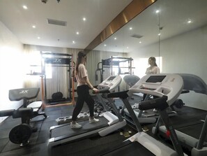 A gym with treadmills, weight machines, and a mirror. - Greentree Eastern Jingde Town Railway Station Hotel (Jingdezhen)