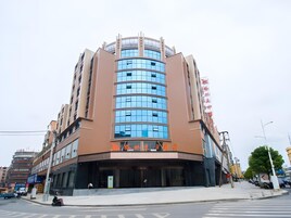 A multi-story hotel with a curved facade, large windows, and a prominent entrance.