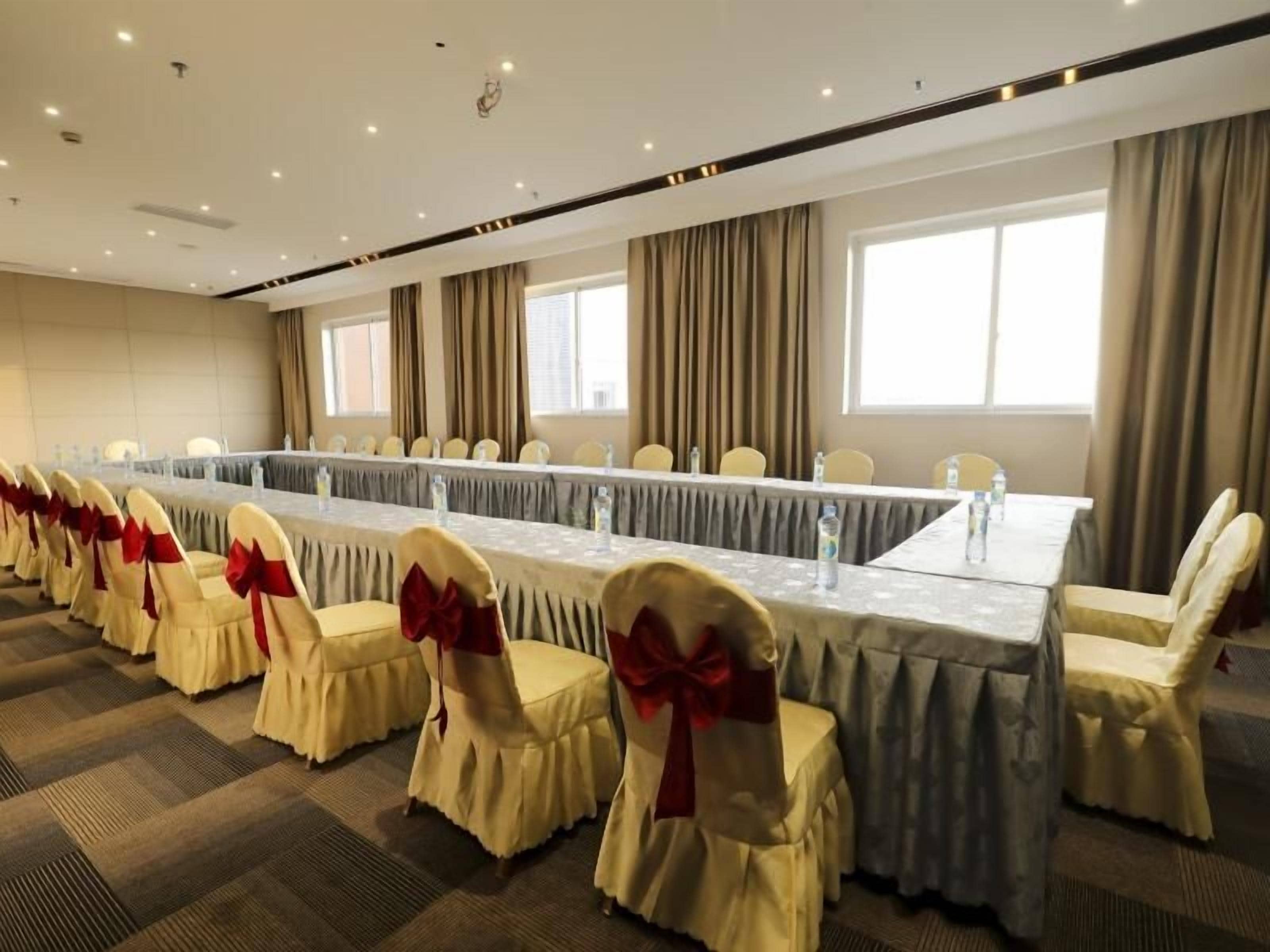 A conference room with a long table, chairs with red bows, and a carpeted floor.
