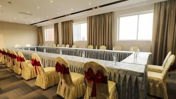 A conference room with a long table, chairs with red bows, and a carpeted floor.