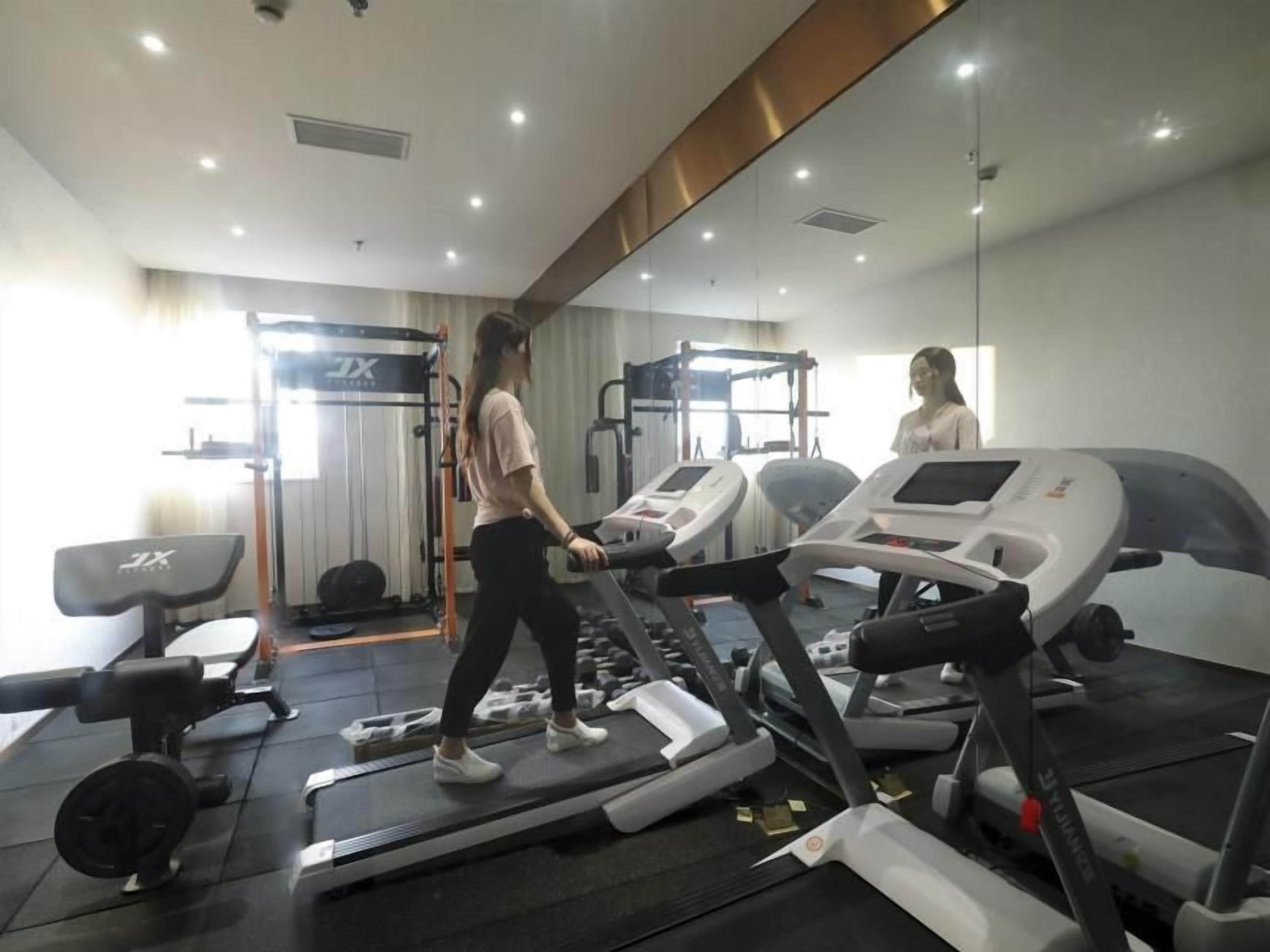 A gym with treadmills, weight machines, and a mirror.