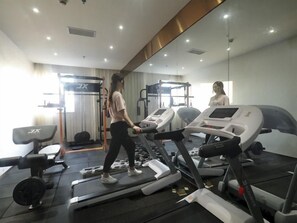 A gym with treadmills, weight machines, and a mirror. - Greentree Eastern Jingde Town Railway Station Hotel (Jingdezhen)