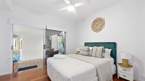 Ein Schlafzimmer mit Bett, Nachttisch, Deckenventilator und einer Wanddekoration.