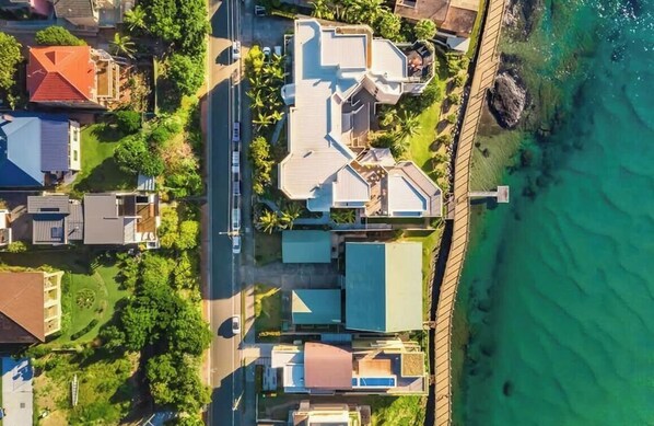 An aerial view of a residential area with houses, a road, and a coastline.