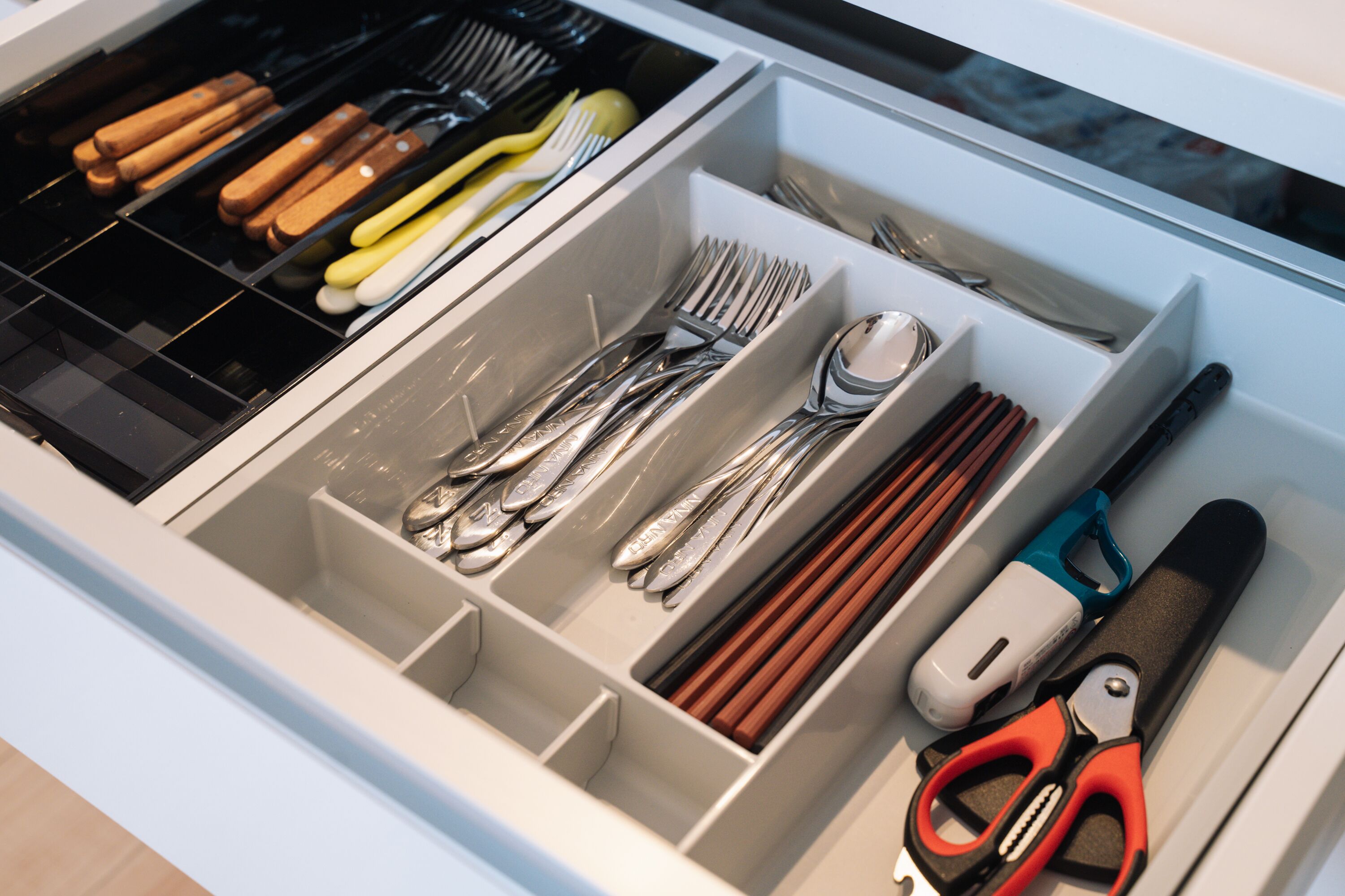 A drawer with utensils and a pair of scissors.